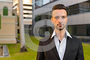 Portrait of handsome young businessman outdoors in city