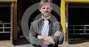 Portrait of a handsome young farmer in shirt looking at camera in background of dairy farm. Agricultural industry