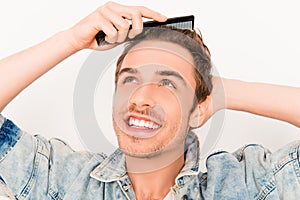 Portrait of handsome young guy combing his hair