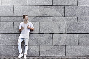 Portrait of a handsome young man in casual clothes enjoying music on your mobile phone, against a brick wall. copy space