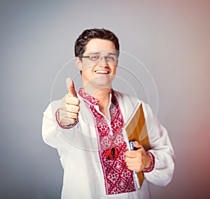 Portrait of handsome young man with copybook and pen on the wond