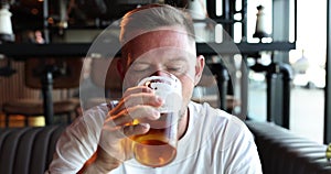 Portrait of handsome young man drinking delicious golden refreshing beer drink in pub