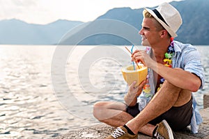 Portrait of a handsome young man enjoying refreshing drink on the beach