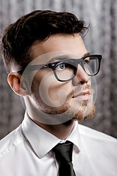 Portrait of handsome young man with glasses and white shirt on grey background