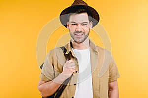 portrait of handsome young man in hat holding backpack and smiling at camera