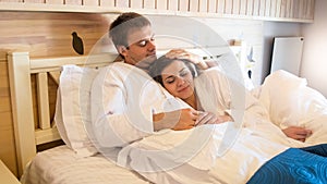 Portrait of handsome young man hugging his wife in bed at hotel