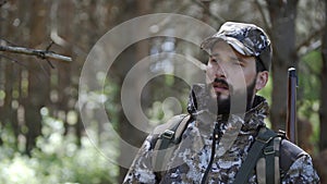 Portrait of handsome young man hunter or tourist. Man in camouflage clothes hunts outdoor in forest hunting alone. Close