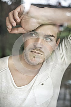 Portrait of handsome young man looking through window