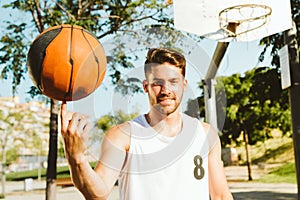 Portrait of handsome young man playing basketball on court.
