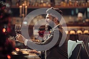 Portrait of handsome young man smiling and holding glass of red wine over blurry background