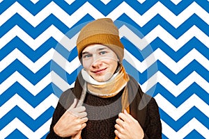 Portrait of a handsome young man smiling wearing warm winter coat, scarf, and funny hat. ready for cold winter weather