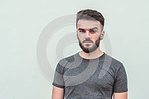 Portrait of a handsome young man standing against gray background. Youth culture. Barbershop