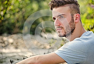 Portrait of handsome young man in white t-shirt in nature photo
