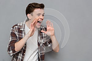 Portrait of handsome young screaming man on gray background