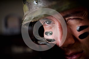 Portrait of handsome young soldier holding in his hands a rifle ready to shoot, winkle his eye to have more precision