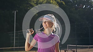 Portrait of hansome woman with tennis racket in the tennis uniform walking outdoor.