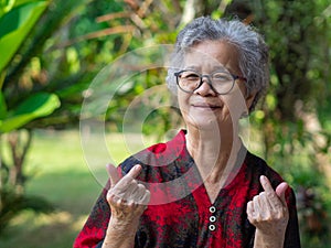 Portrait of happiness senior woman smiling and hands making mini heart while standing in a garden. Concept of aged people