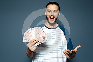 Portrait of happiness young man holding money, Moldovan leu banknotes, on blue.