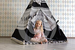 Portrait of happy 3-year-old toddler girl girl smiling while sitting in children play tent