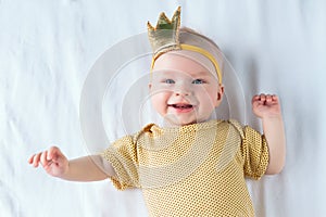 Portrait of happy 4-months-old baby girl lying on the white sheet in bed at home