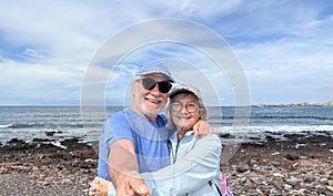 Portrait of happy active senior caucasian couple together in outdoors at the sea beach enjoying vacation and retirement
