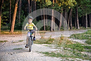 Portrait of happy active teenage boy in safety helmet relaxing after school riding his bike in beautiful park on sunny autumn day