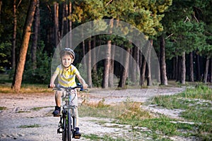 Portrait of happy active teenage boy in safety helmet relaxing after school riding his bike in beautiful park on sunny autumn day