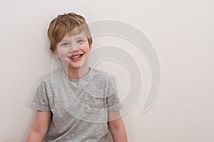 Portrait of happy adorable european boy in casual outfit over white background.Cute blond hair boy in grey T-shirt.