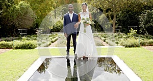 Portrait of happy african american bride and groom at their wedding in sunny garden, slow motion