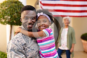 Portrait of happy african american daughter hugging army soldier on return against grandmother