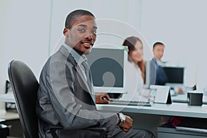 Portrait of a happy African American entrepreneur displaying computer laptop in office.