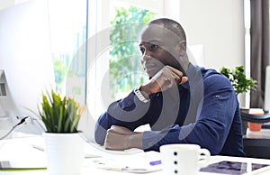 Portrait of a happy African American entrepreneur displaying computer in office.