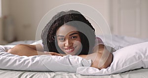 Portrait of happy african american girl lying in bed