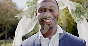 Portrait of happy african american groom smiling at wedding ceremony in sunny garden, in slow motion