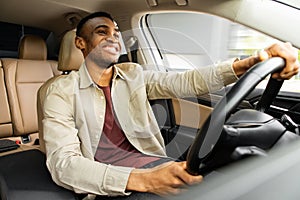 Portrait of happy african american man driving car with beige interior