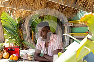 Portrait of happy african american man leaning on counter of surf hire beach shack