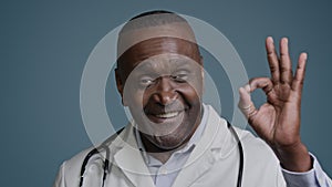Portrait happy african american man smiling male doctor therapist surgeon medical professional worker in studio blue