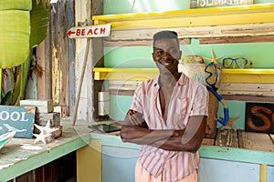 Portrait of happy african american man standing behind counter of surf hire beach shack, copy space