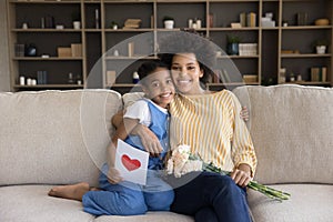 Portrait of happy african american mother cuddling kid daughter.