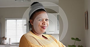 Portrait of happy african american woman looking at camera and smiling at home, in slow motion