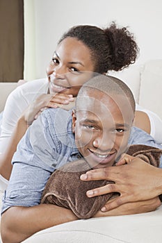 Portrait of happy African American young couple relaxing on sofa