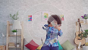 Portrait of a happy african woman with an afro hairstyle in sunglasses throwing out money banknotes