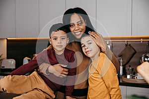 Portrait of happy afro american family in the kitchen, mom and two sons looking at the camera