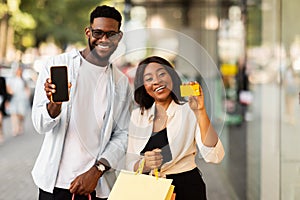 Portrait of happy afro couple using smartphone holding credit card