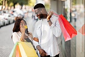 Portrait of happy afro woman showing credit card to man