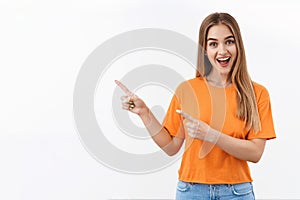 Portrait of happy, amazed and enthusiastic blonde female caucasian student, girl pointing fingers upper left corner to