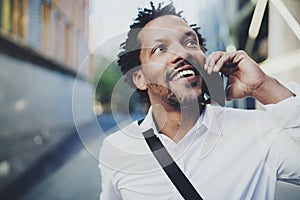 Portrait of happy American African black man using mobile phone to call friends at sunny street.Concept of happy young