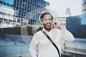 Portrait of happy American African man using smartphone to call his friends at sunny city.Concept of happy young