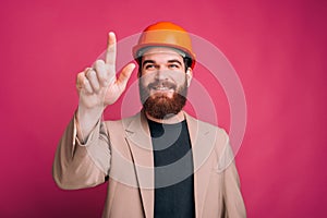 Portrait of happy architect pointing away and smiling over pink background