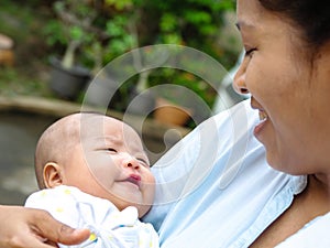 Portrait of happy Asia mother holding his newborn sweet baby dressed. The mommy embracing her baby with love and care. her daughte